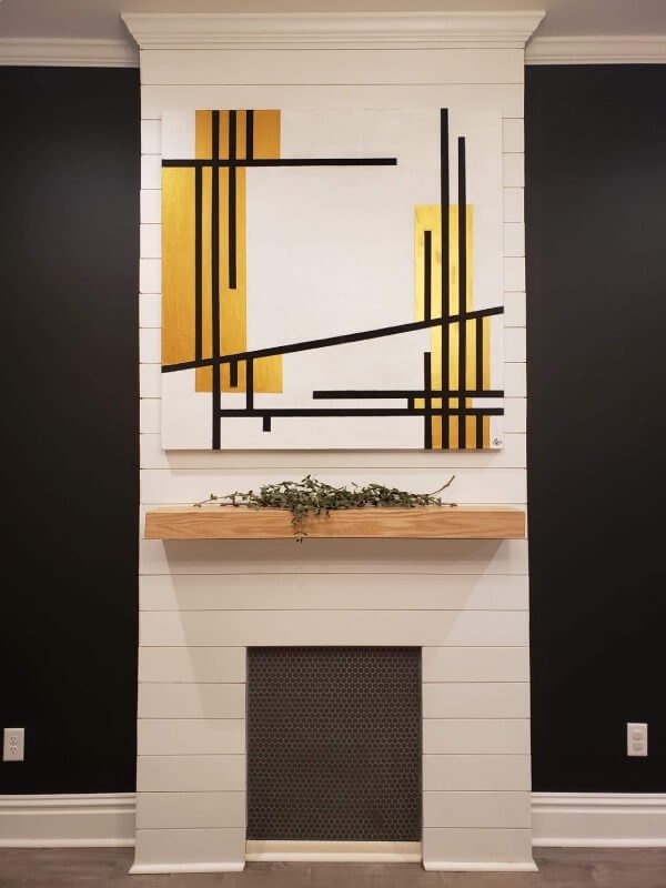 White and gold painting with black lines above fireplace